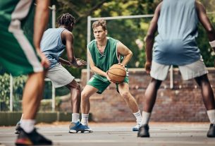 Basketball, team sport and competition for male athletes and players in training or professional match on an outdoor fitness court. Diversity, competitive and skill of men playing a ball game in USA